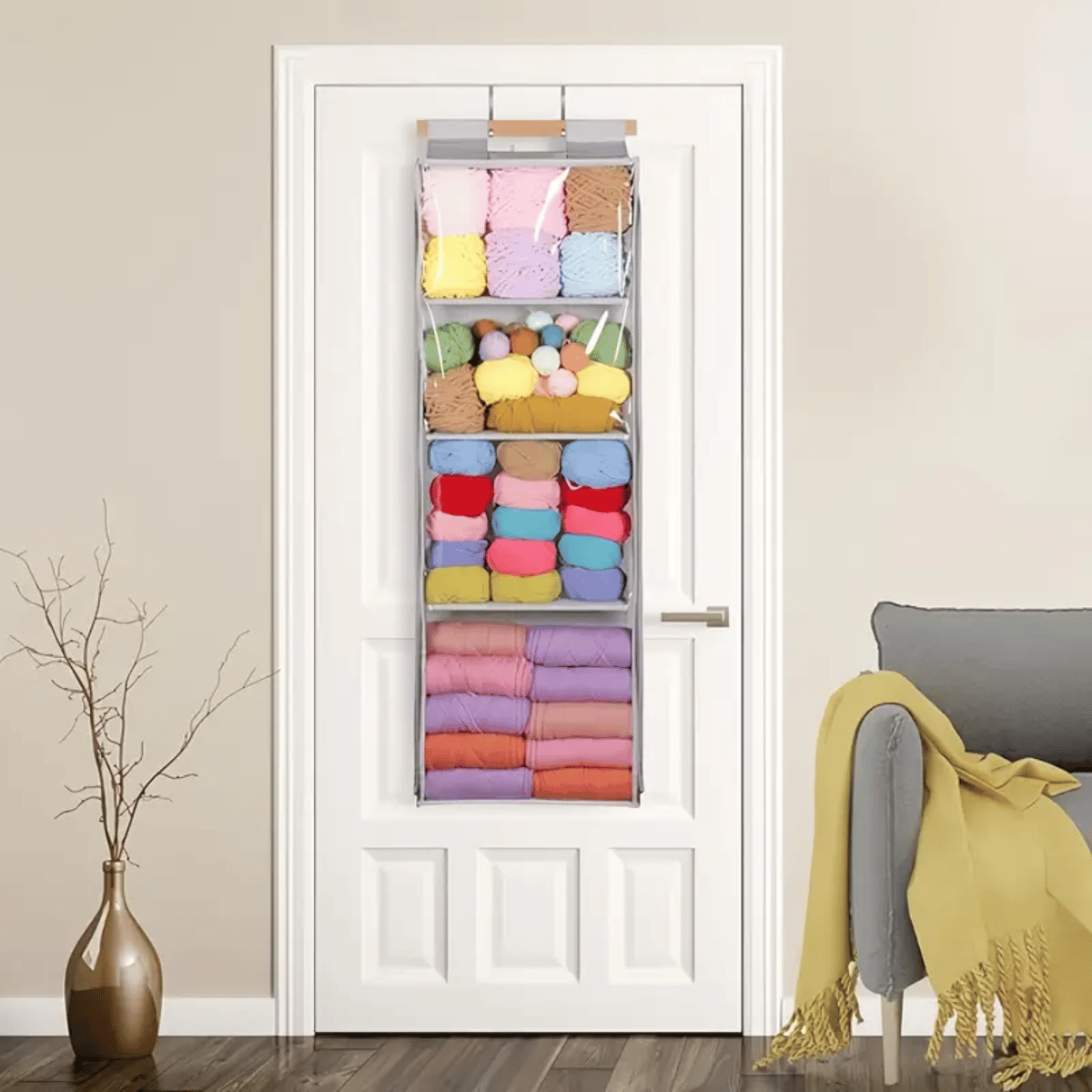 The Hanging Yarn Storage Organizer, filled with neatly arranged yarn skeins and craft supplies, hangs on a white door in the living room, making it an ideal storage solution.