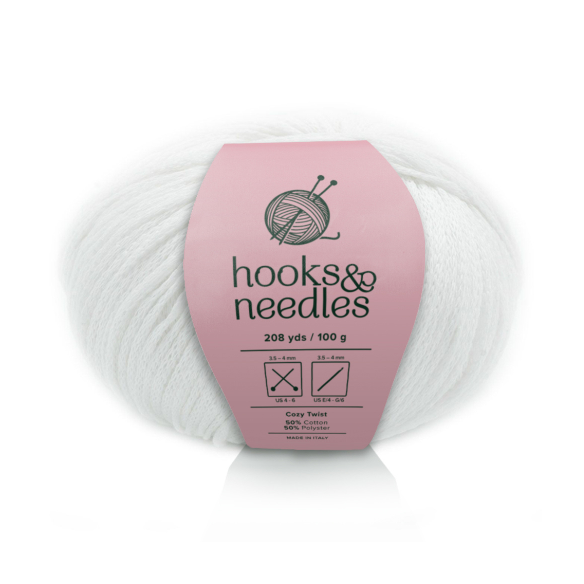 A skein of Cozy Twist yarn in white with a pink "hooks & needles" label displays material details, length, weight, and recommended needle sizes—ideal for soft, durable, and versatile projects.