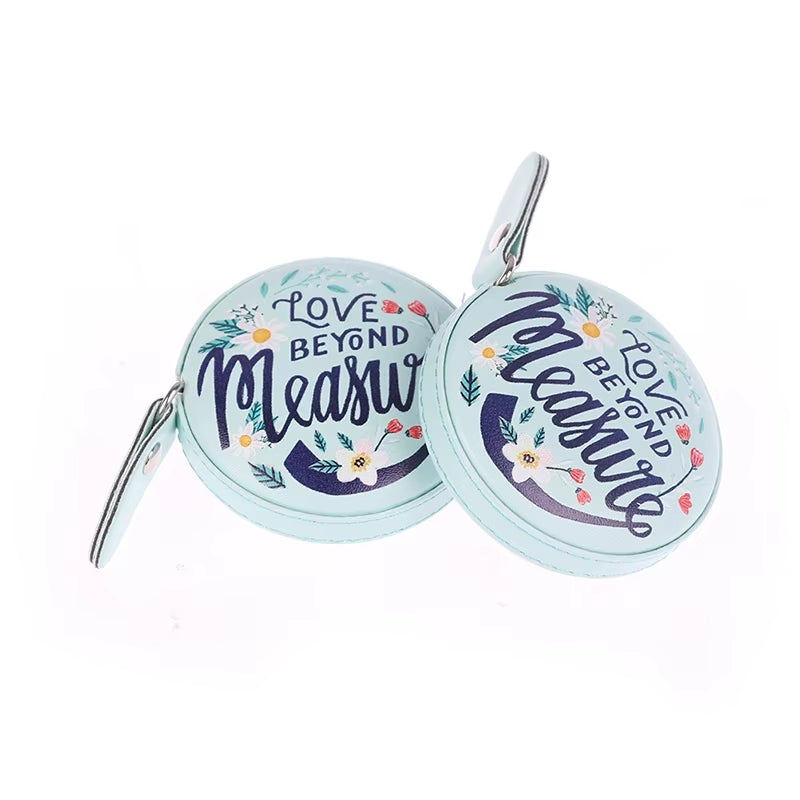 The package includes a pair of round turquoise compact mirrors featuring floral designs and "Love Beyond Measure" text on the cover, alongside a 150cm/60in retractable measuring tape, which is an indispensable tool for knitting and crocheting.