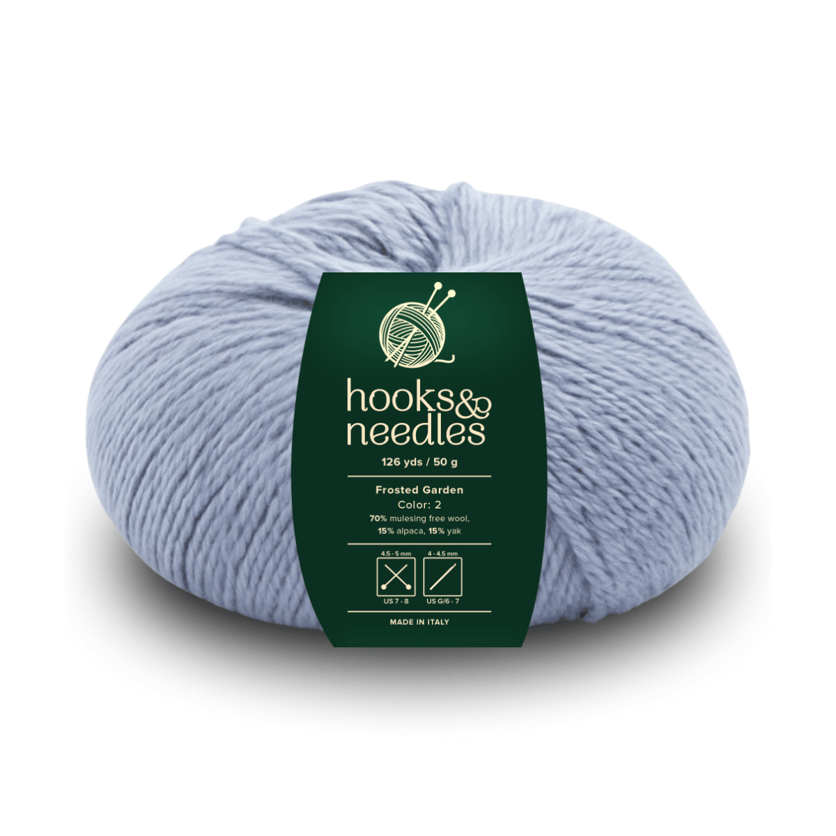A skein of Frosted Garden in light blue, 126 yds/50g, features a green "hooks & needles" label and is crafted from ethical cotton and mulesing-free wool—ideal for mindful, cozy projects.