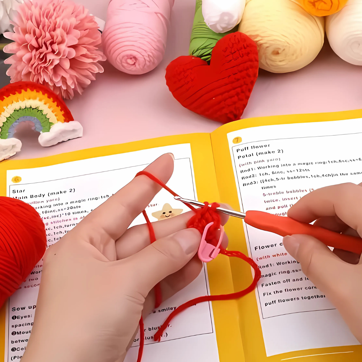 Crocheting with red yarn and a hook, guided by an open pattern book, and surrounded by colorful yarn—ideal for beginners using the Crochet Keychain Kit 4pcs to make handmade keychains.