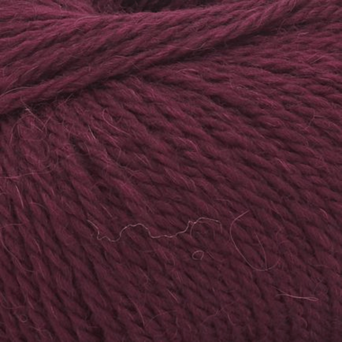 Close-up view of a ball of Aurora Gemstones, a dark burgundy cotton-acrylic yarn that perfectly highlights its texture and strands—ideal for lightweight, breathable projects.