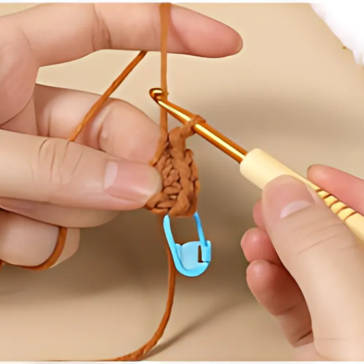 Hands holding a crochet hook and brown yarn, working on a handmade home decor piece with a blue stitch marker—ideal for beginners using the Plant Pot Crochet Kit with Coasters or anyone exploring a new crochet project.