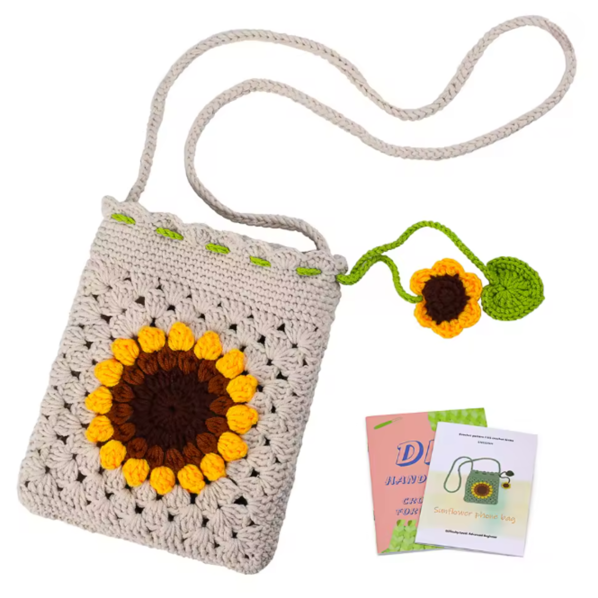 The Sunflower Crochet Bag Kit features a crocheted shoulder bag with a sunflower design, a green leaf and flower charm on the strap, plus two small booklets—an ideal floral accessory for crochet bag enthusiasts.