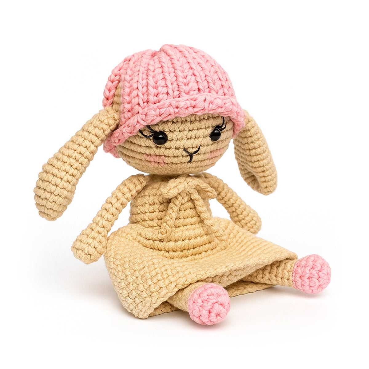 Rosie The Bunny Crochet Pattern features a cute crocheted bunny with long ears, pink hat, beige dress, and pink feet. This adorable design sits upright and is perfect for beginners or anyone seeking a charming crochet bunny project.