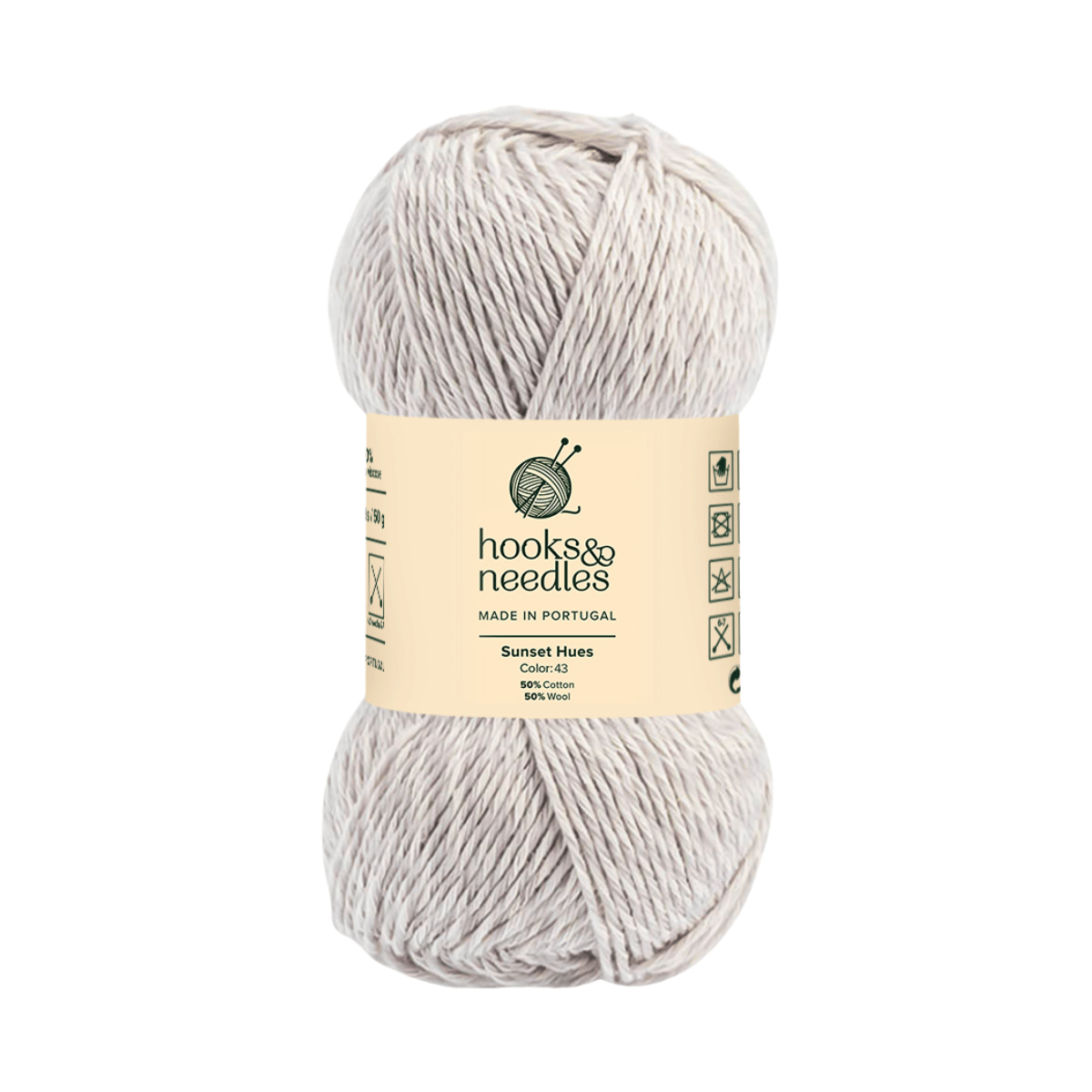 A skein of off-white Sunset Hues Yarn featuring care instructions, fiber content, and color details on the label—ideal for all your yarn crafting projects.