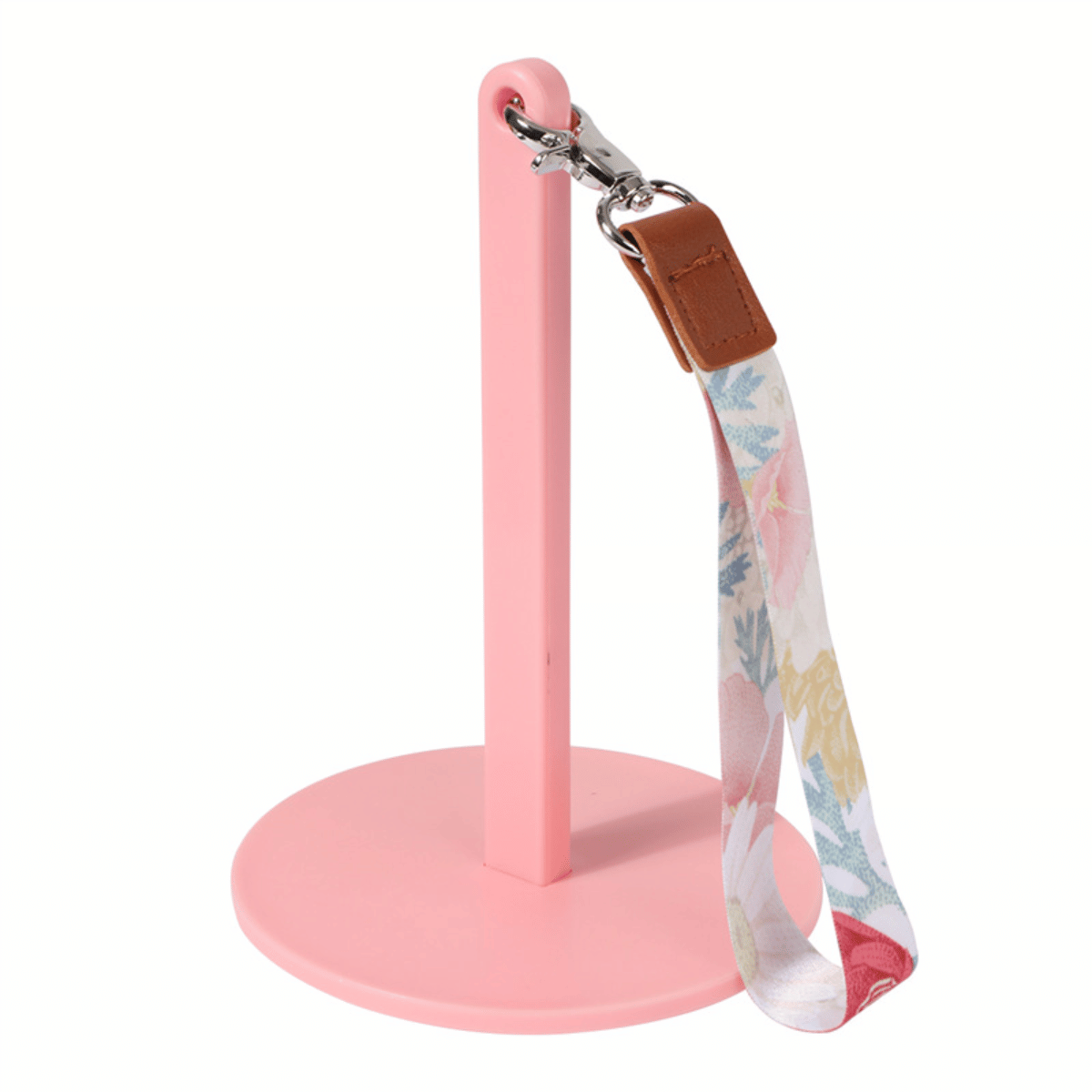 The Wrist Yarn Holder features a pink vertical stand with a round base, and includes a floral-patterned fabric wrist strap with metal clasp and brown leather accent—ideal for travel, crafting, or hands-free yarn control.