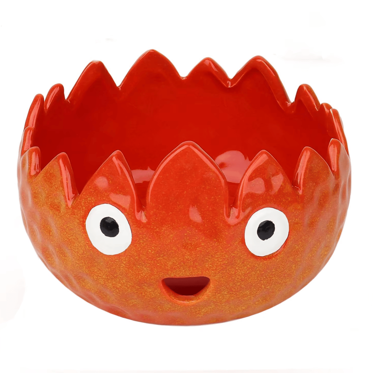 The Flame Ceramic Yarn Bowl features a jagged rim and a cheerful face with wide eyes and a small mouth, making it a fun and stylish way to hold your crochet or knitting accessories.