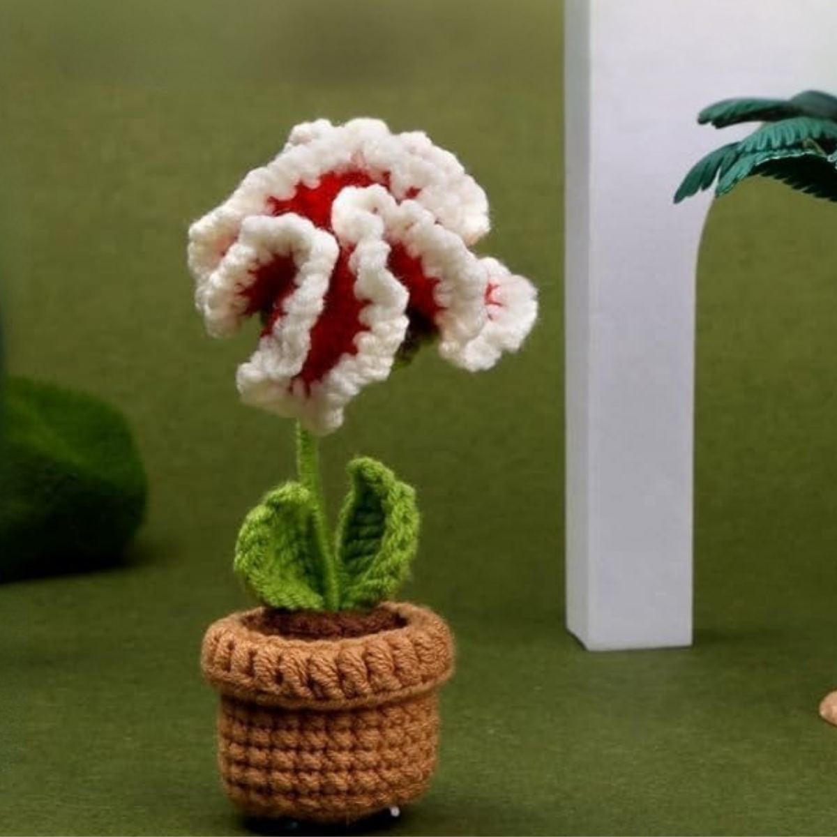 The Crochet Flower Pot Kit 6pcs features white and red crocheted flowers with green leaves in brown pots, ideal for displaying handmade creations or starting your crochet journey.