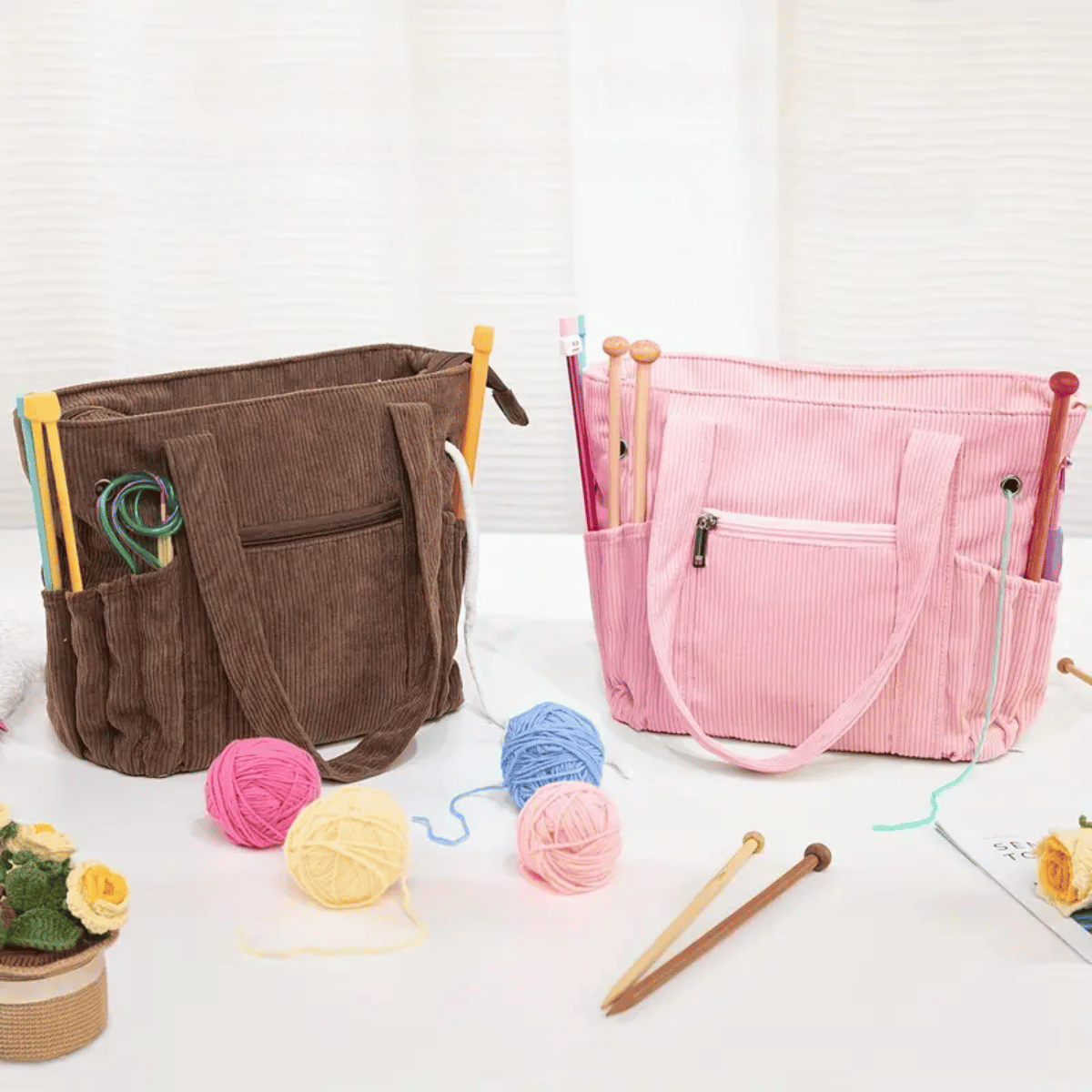 Two Crochet & Knitting Organizer Totes—one brown, one pink—hold needles and tools, surrounded by yarn balls, a flame ceramic yarn bowl for tangle-free crafting, and knitting accessories on a white tabletop.