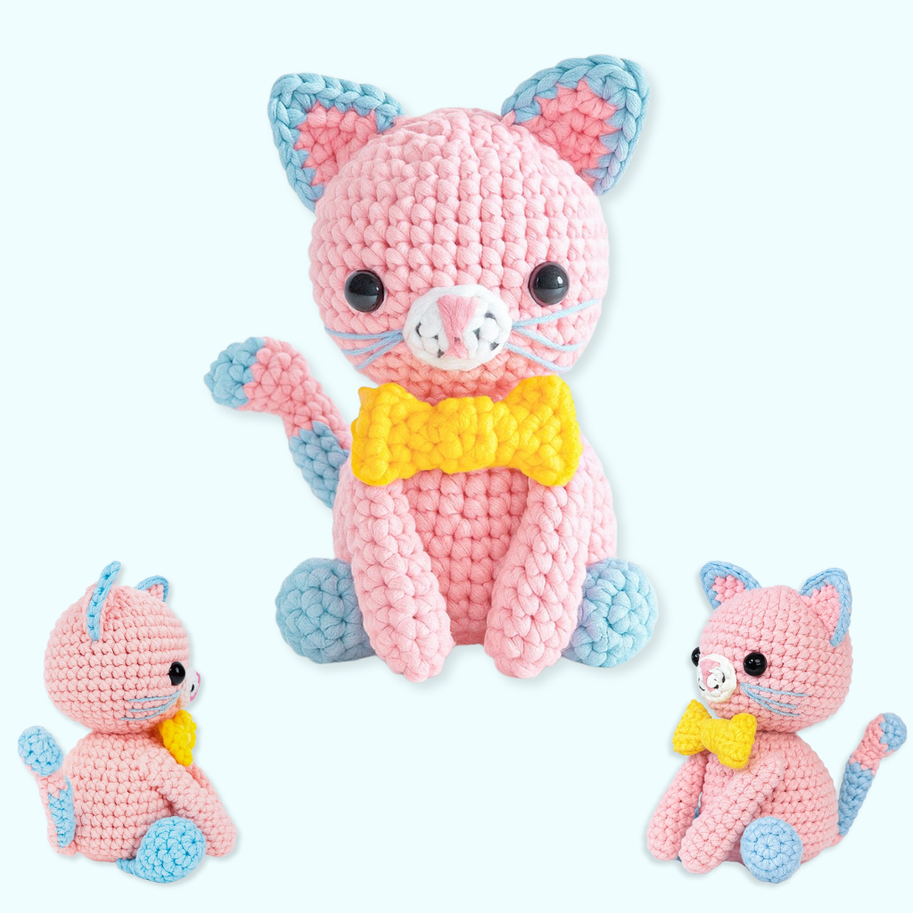 One of The Snuggle Squad's 10 adorable crochet patterns features a pink amigurumi cat with blue ears, tail, and paws, large black eyes, and a yellow bowtie, displayed from three angles.