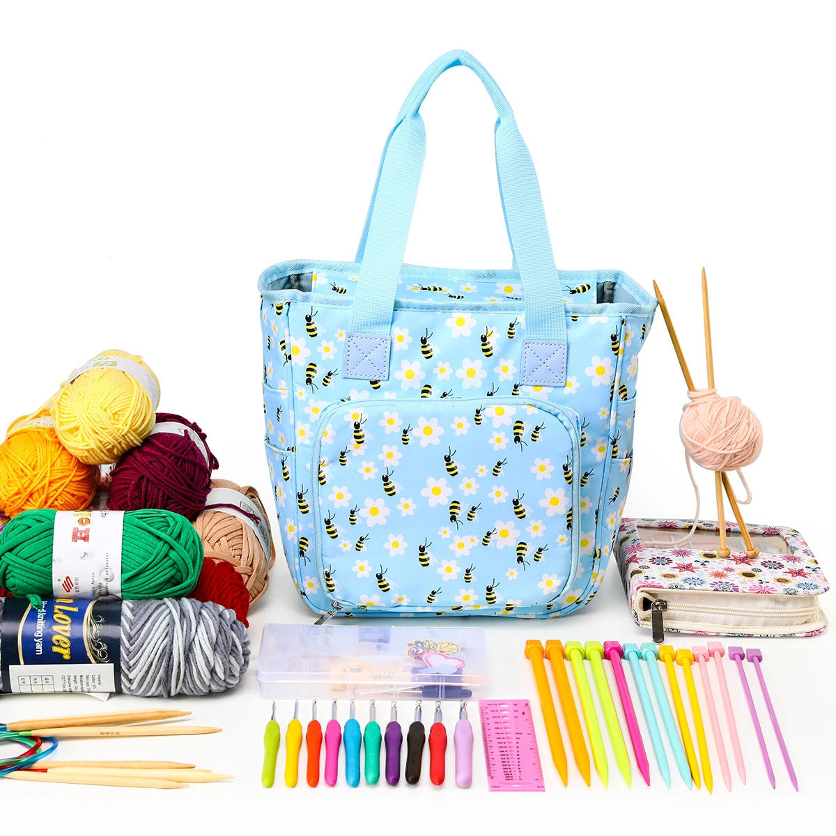The Multifunctional Knitting Tote Bag: Yarn Storage Organizer (Bundle31) in blue floral design, surrounded by yarn, knitting needles, crochet hooks, a pattern book, and a measuring tape, is ideal for organizing all your knitting supplies.