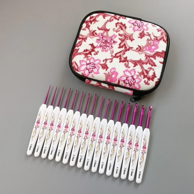 The Crochet Hook Set 16 Pcs with Case, showcasing artistically decorated handles, is elegantly arranged in a row next to a floral-patterned zippered case on a gray surface.