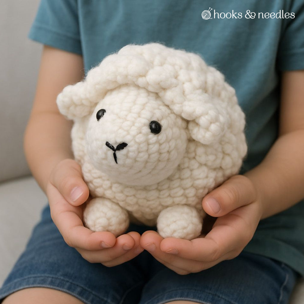 A person holds a small baby lamb plush made from the Baby Lamb Stuffie Crochet Pattern—ideal inspiration for intermediate crocheters seeking a new project.