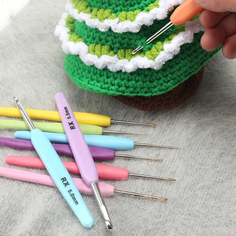 An Ergonomic Crochet Hook Set 16 Pcs with Case is positioned beside a green and white crocheted piece, as a hand grasps an ergonomic crochet hook specifically crafted for those with arthritis.
