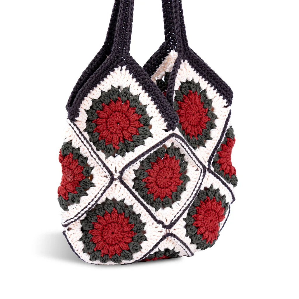 The DIY Granny Square Crochet Tote Bag Kit features diamond-shaped squares in red, green, and white with dark borders plus two crocheted handles—ideal for crafters and includes beginner-friendly instructions.