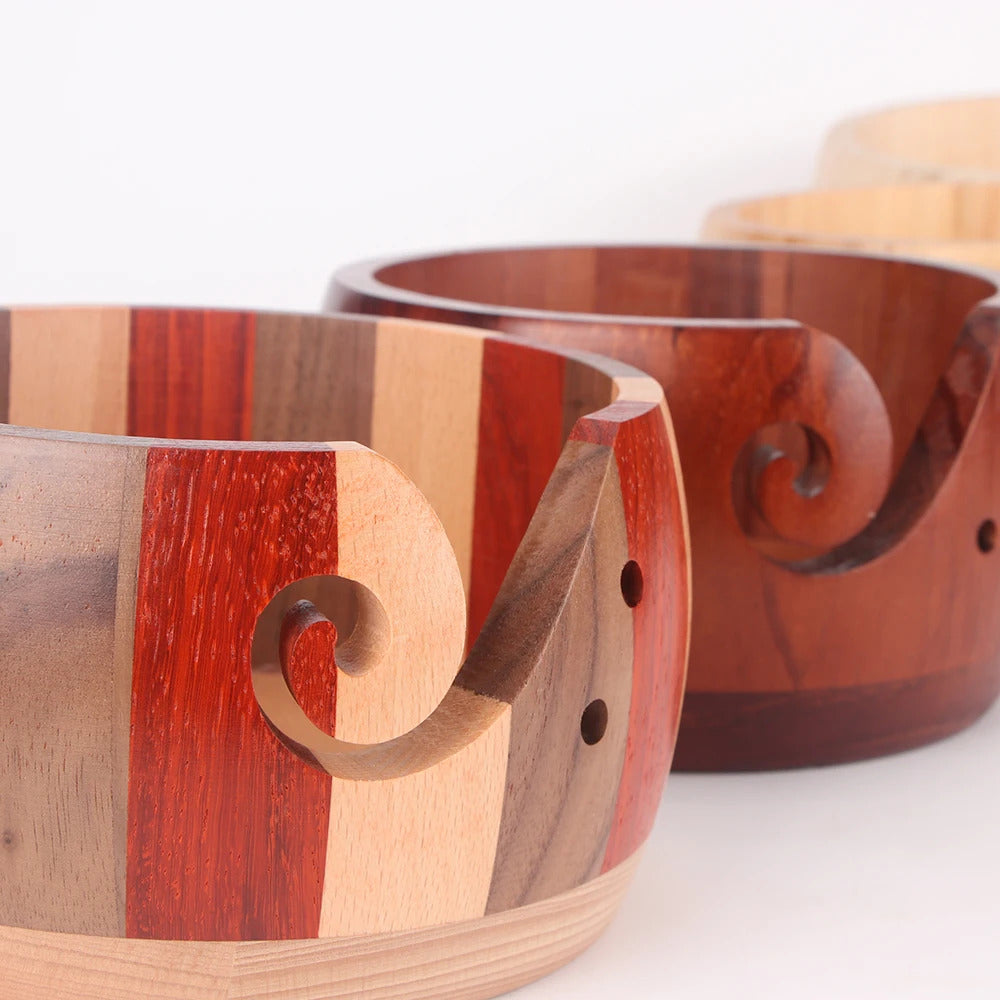 Three Handmade Wooden Yarn Bowls, each in different brown hues and showcasing elegant carved swirl cutouts on one side, are arranged in a row.