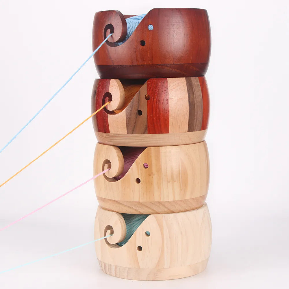 A set of four Handmade Wooden Yarn Bowls, each adorned with a decorative cut-out swirl design, elegantly holds yarn strands as they extend outward.