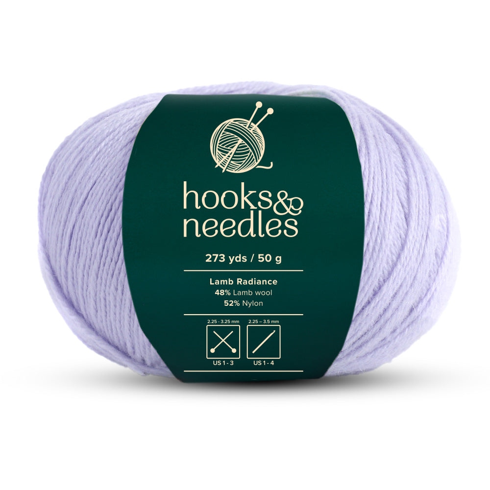 The Lamb Radiance Yarn 50g, in soft lavender, is a super fine-weight yarn labeled "hooks & needles," offering 273 yards per skein. It features a blend of 48% lamb wool and 52% nylon.