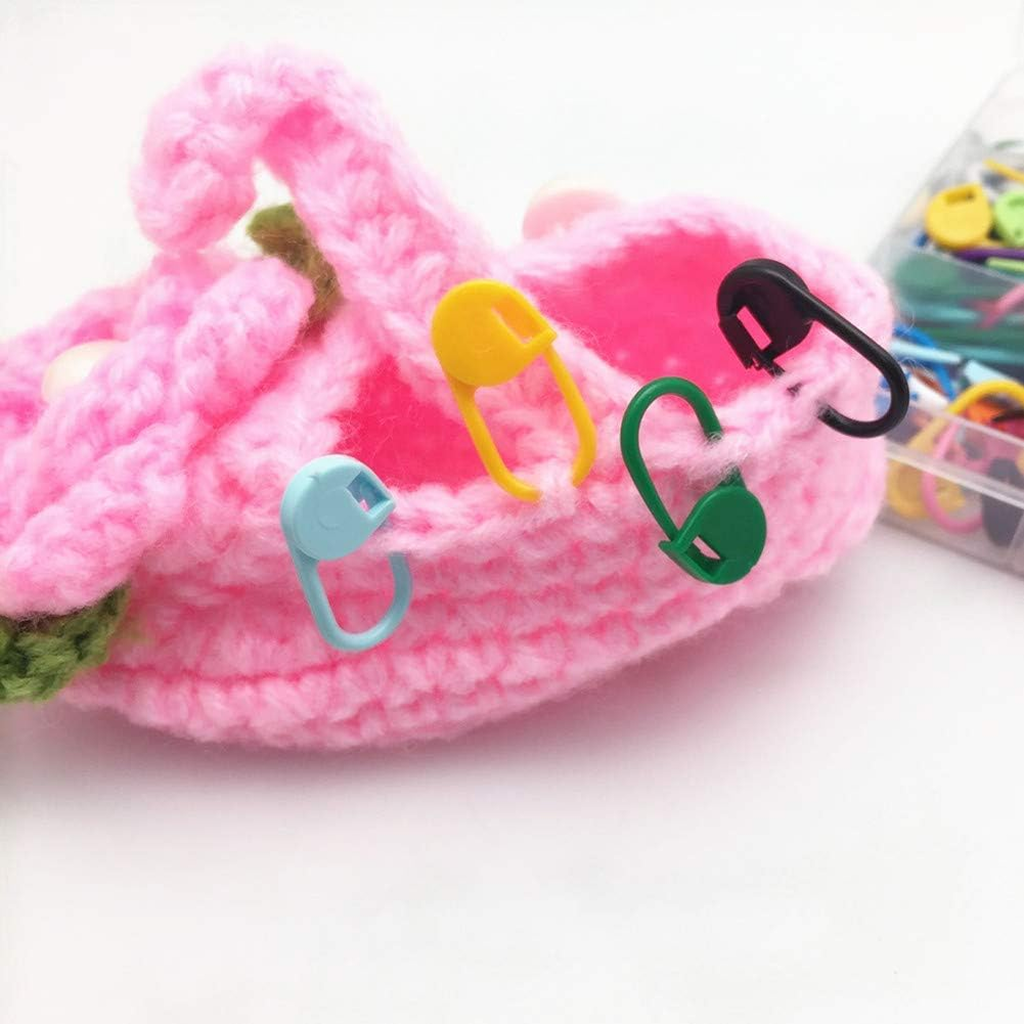 A pink crocheted piece with Colorful Plastic Stitch Markers attached rests beside a container of extra markers—an ideal arrangement for yarn crafts.