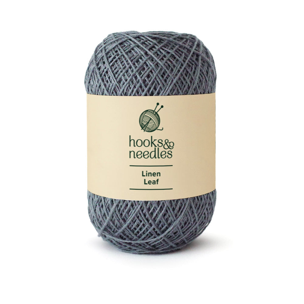 The Linen Leaf Yarn 50g from Hooks & Needles brand, featuring a cream label with a knitting needles logo, is ideal for crafting breathable garments or intricate lace projects.