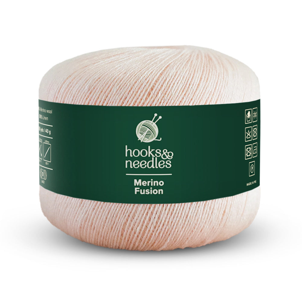 A ball of lace-weight yarn in light pink, branded as "Merino Fusion Yarn 40g." The dark green label with white text and symbols emphasizes the superior quality of the merino wool used.