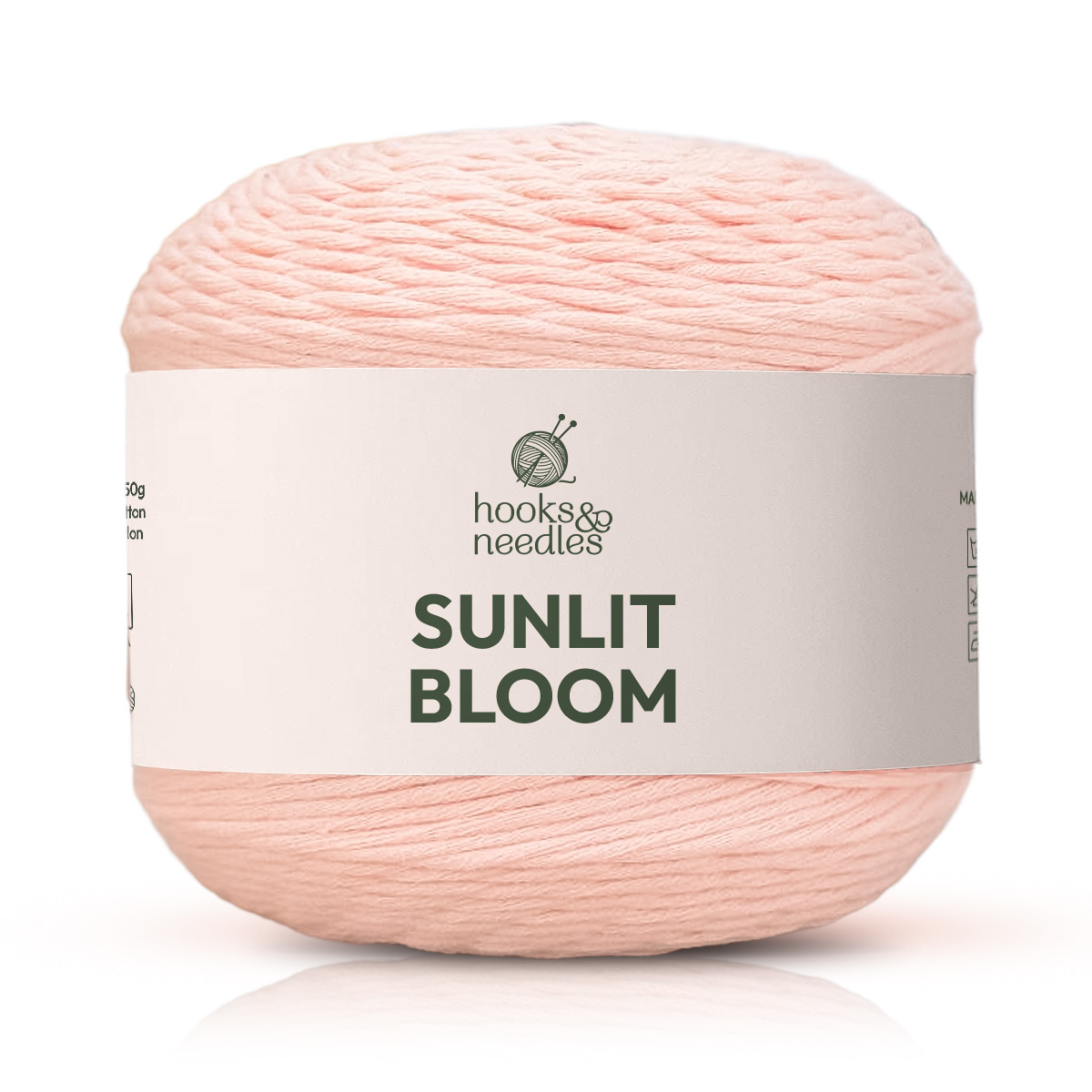 Sunlit Bloom Yarn is a soft, light pink cotton yarn with a white wrapper and green text—ideal as a medium weight yarn for making breathable, comfortable projects.