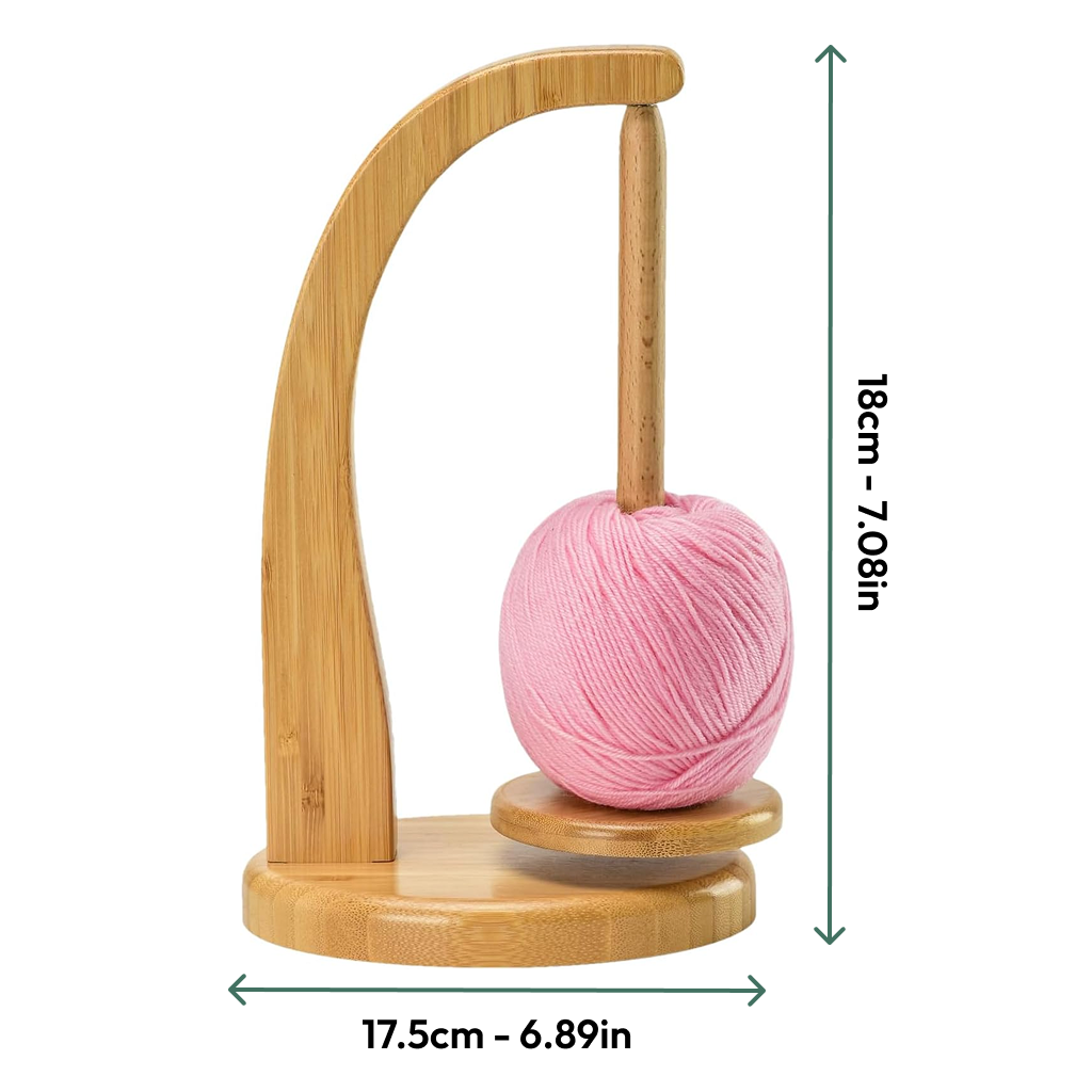 The Levitating Premium Yarn Holder is a wooden yarn holder with a vertical rod that holds a pink yarn ball. It has a magnetic design for seamless knitting and measures 18 cm tall by 17.5 cm wide.