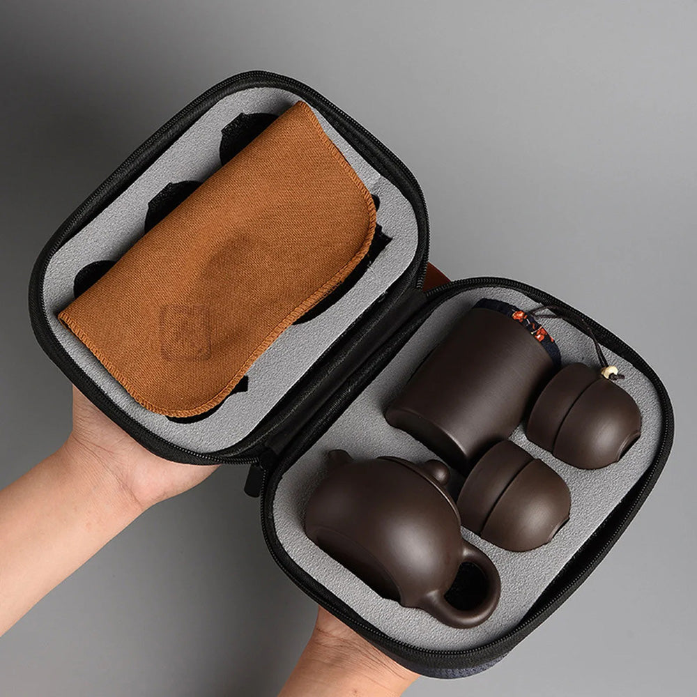 Introducing the Tea Set with Case (Bundle24), a portable tea set that comes in a zippered case complete with a brown cloth. It includes a teapot and two matching cups, making it an ideal companion for tea enthusiasts on the go.