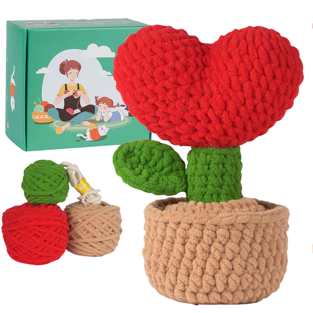 The Crochet Heart Plant Kit features a plush red heart-shaped plant with green leaves in a knitted beige pot, plus two yarn balls and a green family-themed box—perfect for DIY crochet home decor.