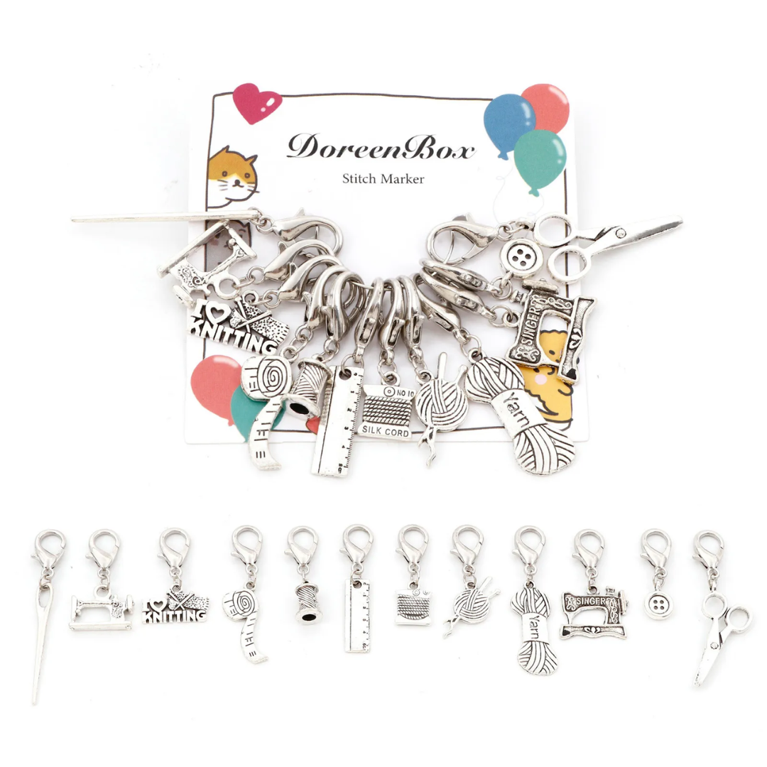 Displayed on a white background, the Stitch Markers 12pcs set is made of durable steel and includes silver charms with a knitting theme. Ideal for precise stitch marking, these markers offer both functionality and an attractive design.
