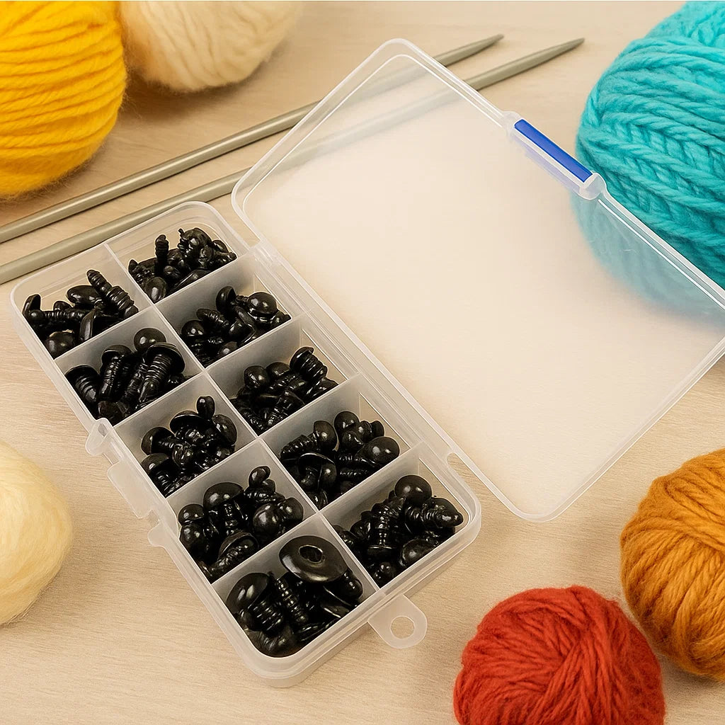 The Safety Eyes for DIY come in a plastic organizer box with black eyes, ideal for amigurumi and crochet projects—shown with yarn balls and metal knitting needles on a wooden surface.