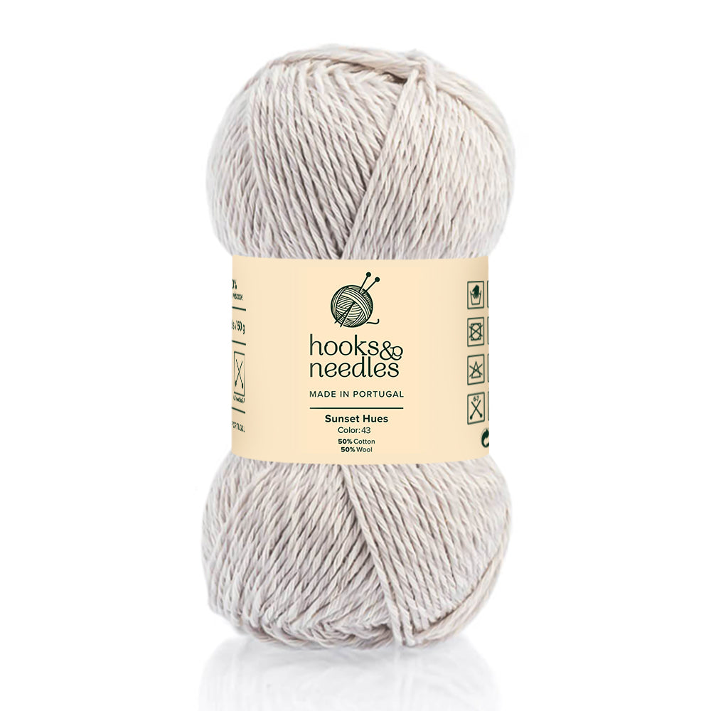 A skein of Sunset Hues Yarn 50g, cream-colored and sustainable, made in Portugal from a 50% cotton, 50% viscose blend, displayed against a white background.