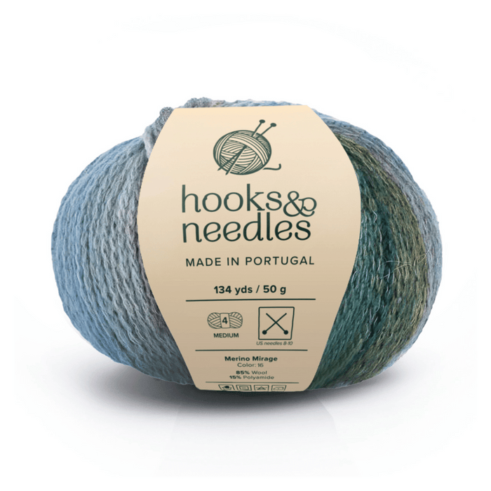 A 50g, 134-yard ball of Merino Mirage luxury yarn (85% Merino wool, polyamide) in blue-green variegated "Mirage" color, labeled hooks & needles, made in Portugal.