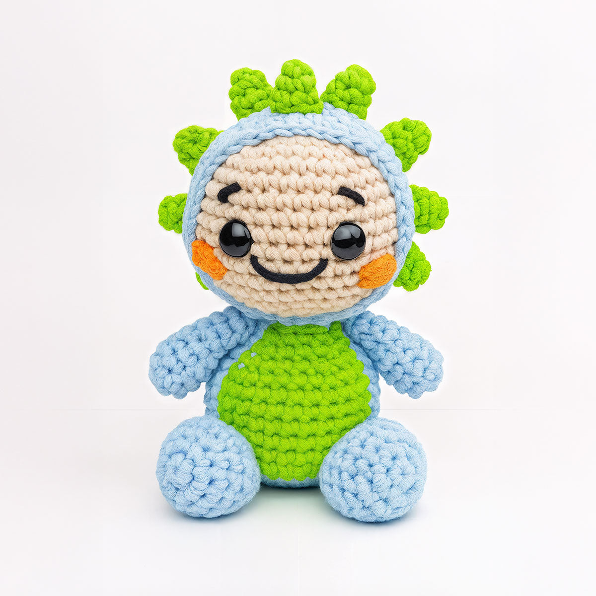 Spiky The Dino is a crocheted plush toy featuring a blue and green body, round black eyes, a smiling face, and spiky green details on its head, displayed against a plain white background.