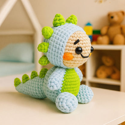 Spiky The Dino, a crocheted plush toy with a green belly and spikes, crafted from an advanced crochet pattern, resembles a dinosaur and sits on a table in a cozy, softly lit room.