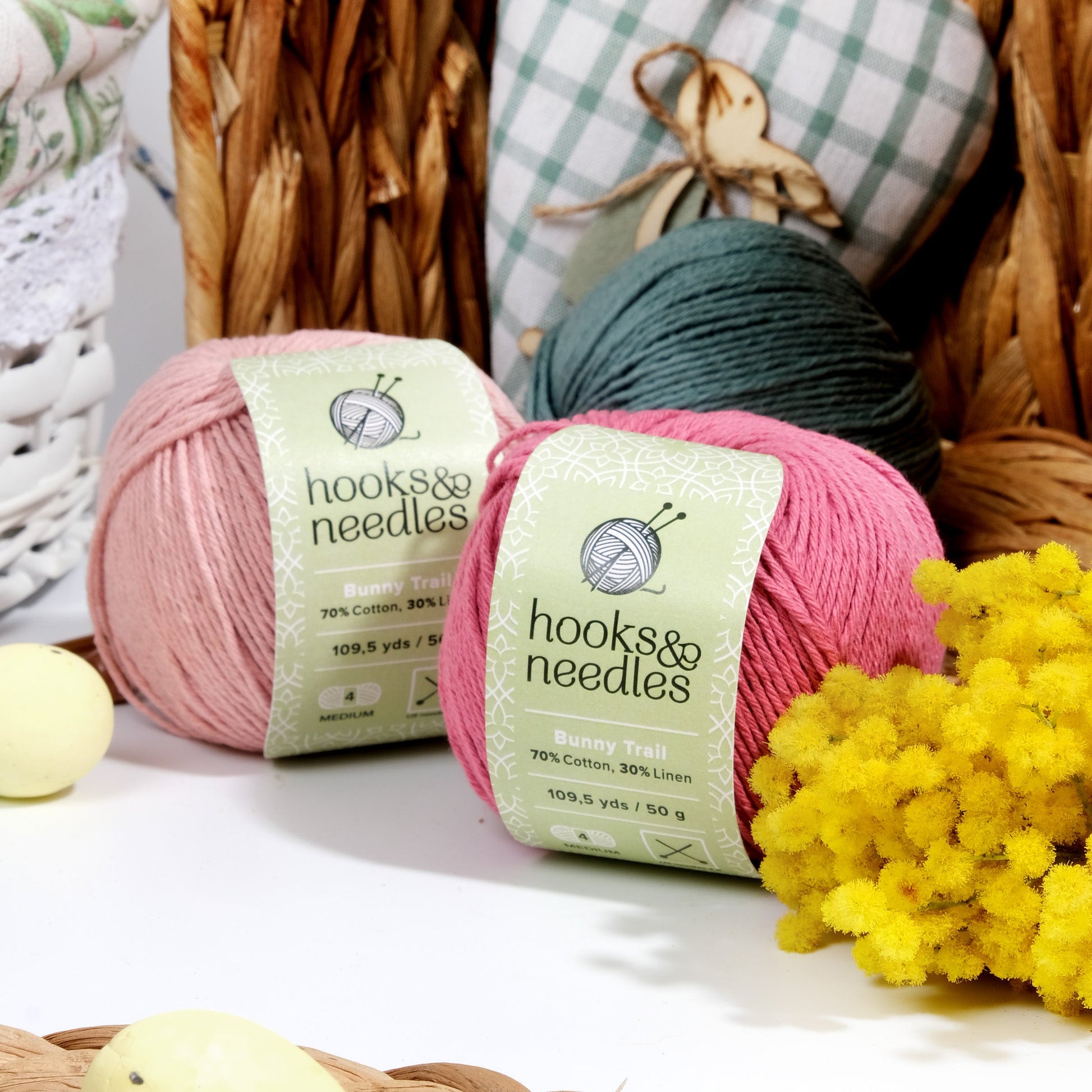 Two balls of Limited Edition Easter Special Collection (bundle) yarn with 'hooks & needles' labels, accompanied by decorative items in a craft setting.