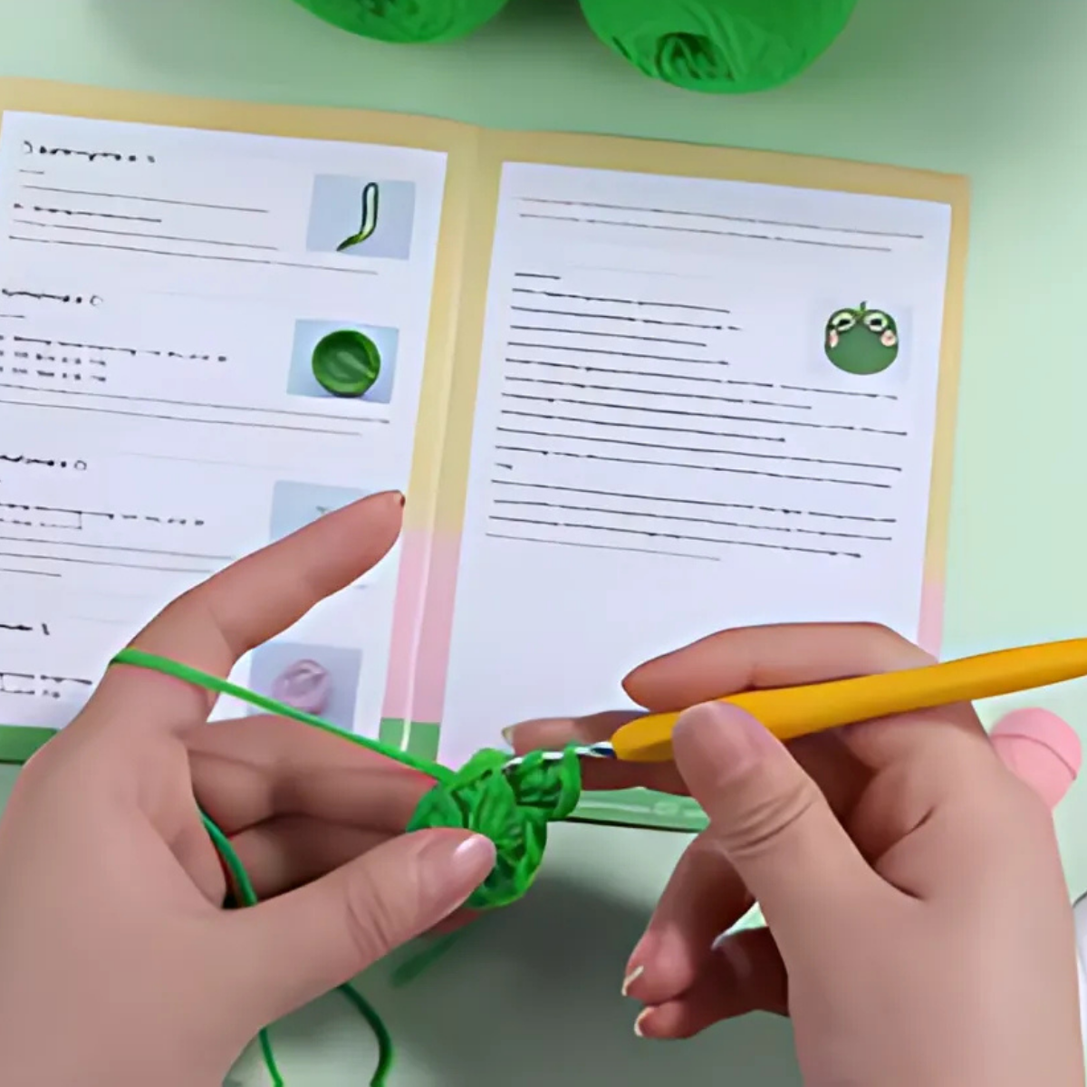 Using the Frog Storage Bag Crochet Kit, a person crochets with green yarn and a yellow hook while following illustrated booklet instructions on a table, creating a whimsical frog-shaped storage bag.