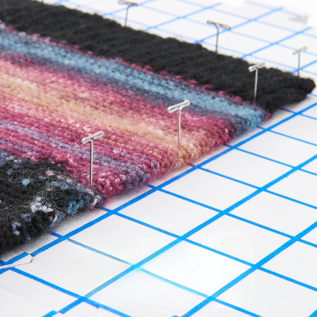 A multicolored knitted fabric is pinned on a grid blocking mat using T-Pins For Blocking, which are durable and rust-resistant.