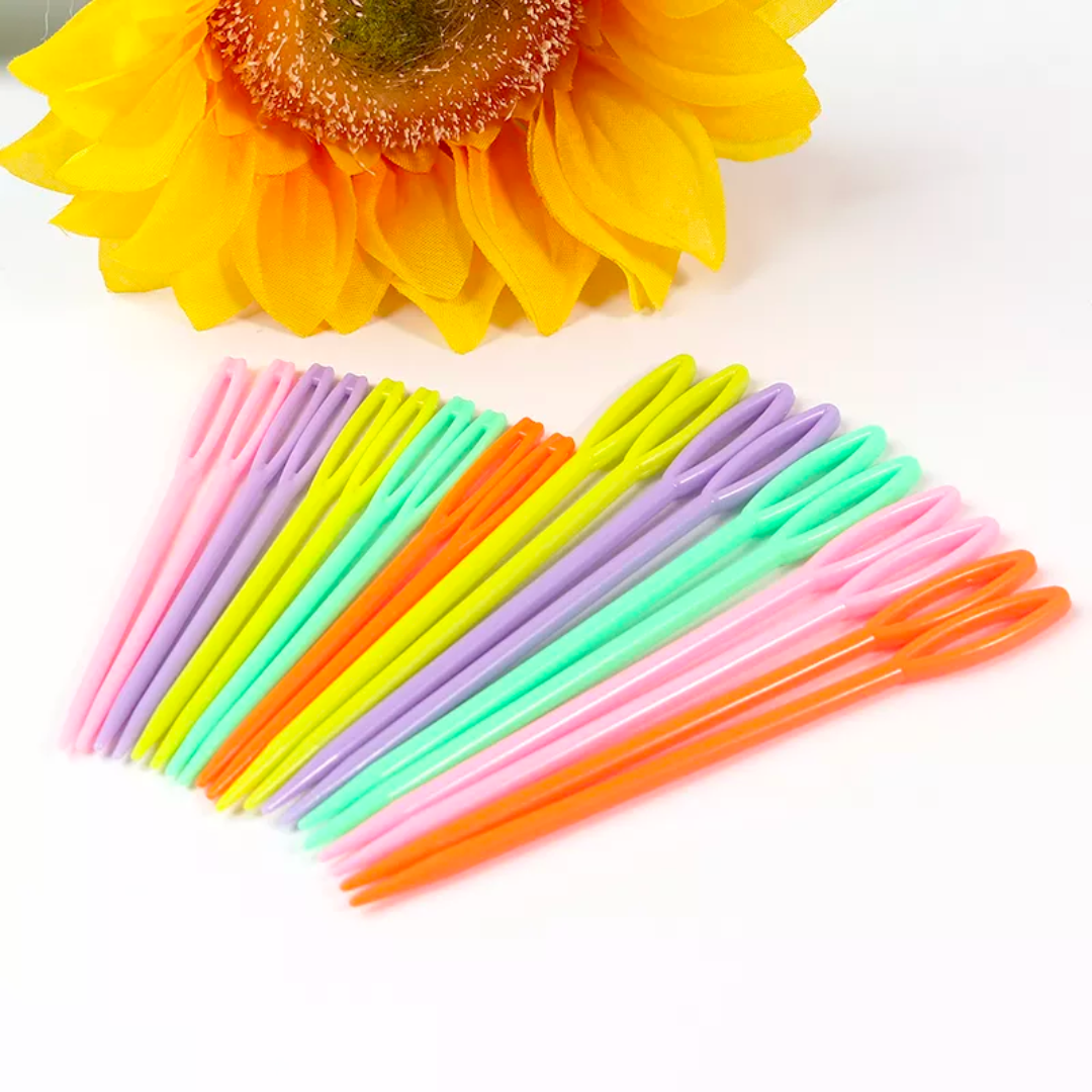 A collection of Colorful Plastic Yarn Needles 20pcs arranged in a fan shape beside a sunflower.