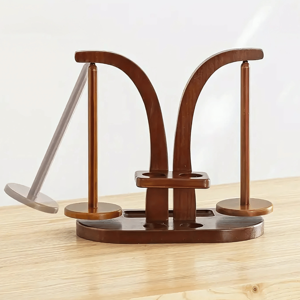 The Double Yarn Spinner Stand with Tool Storage features two curved arms and round bases in brown wood, providing elegant, tangle-free yarn organization on a light wood surface against a plain background.