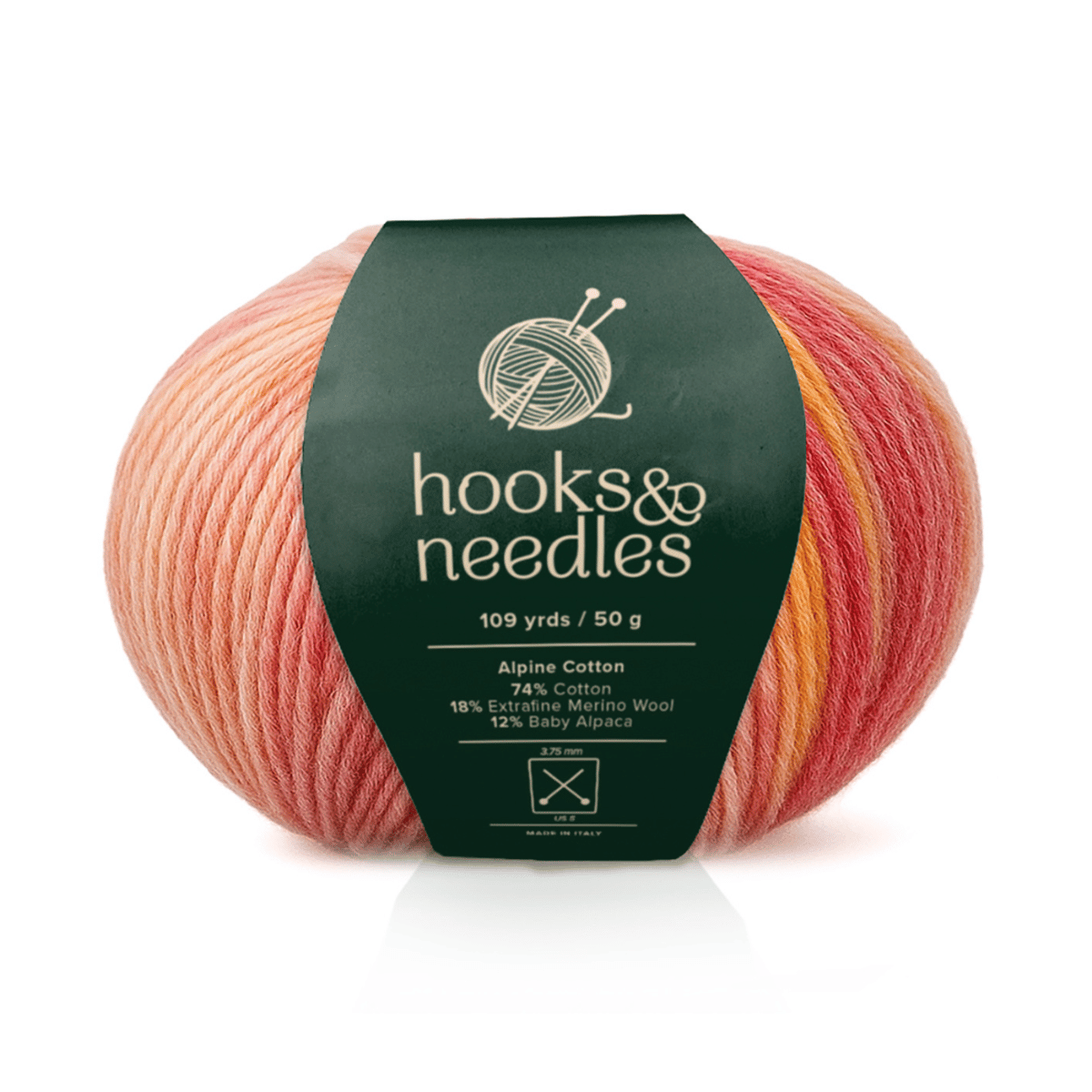 A bulky ball of Alpine Cotton yarn in a pink and orange gradient, with a green "hooks & needles" label detailing its cotton-viscose blend and yardage.