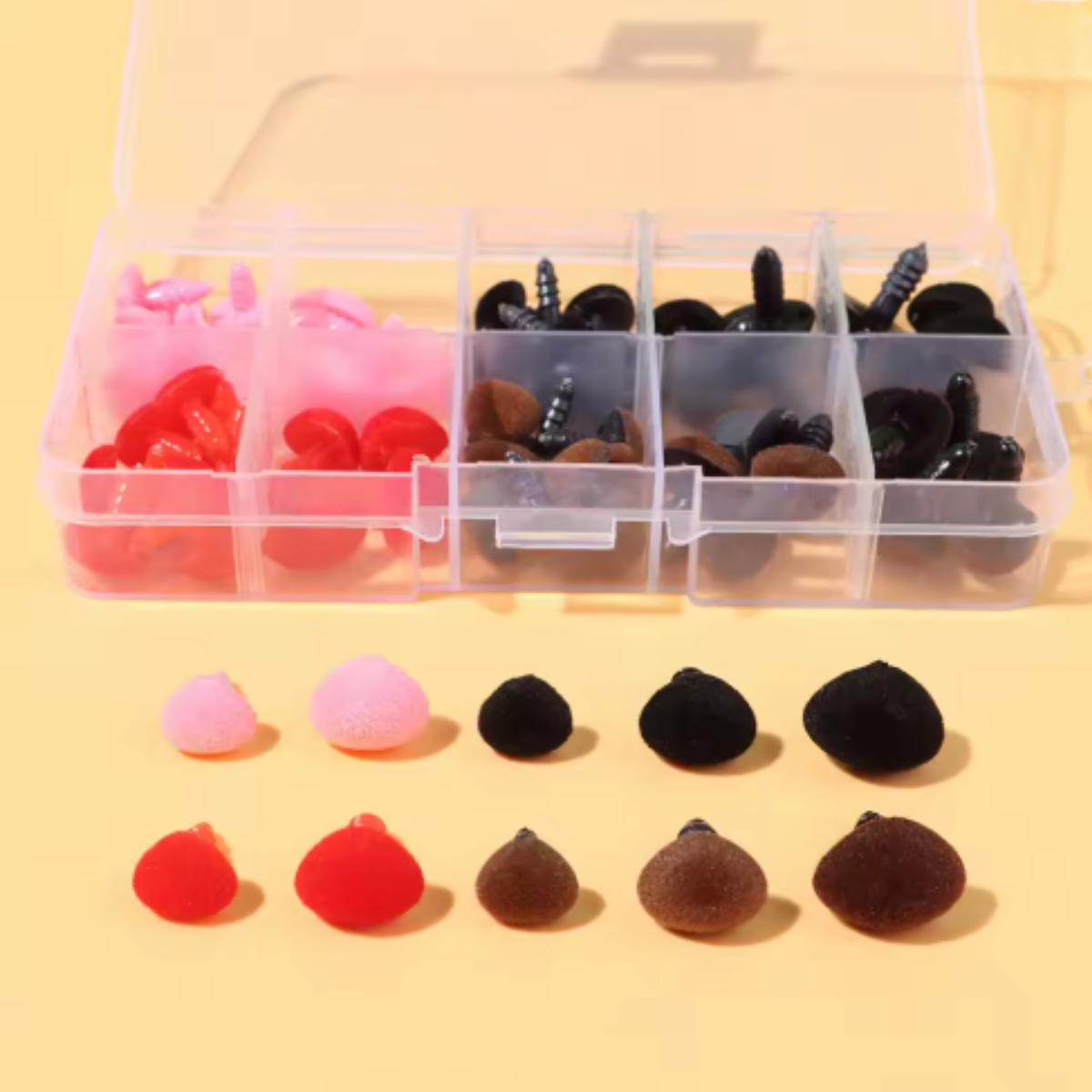 The Safety Noses for Toys with Washers set includes round, textured noses in pink, red, brown, and black stored in a plastic organizer box—ideal for crochet toys or amigurumi—with matching pieces shown in front.