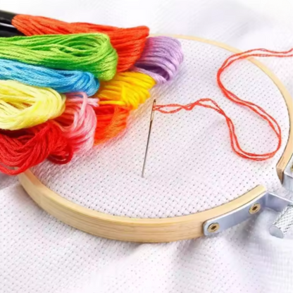 The Embroidery Floss Set includes an embroidery hoop with white fabric, a threaded needle, and several colorful floss skeins—perfect essentials for detailed cotton thread work.