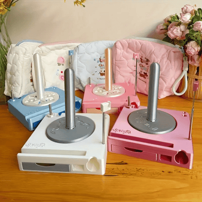 The Spinning Yarn Holder with Tool Storage comes in blue, white, pink, and rose pink, displayed on a wooden table beside three patterned pouches and a vase of flowers in the background.