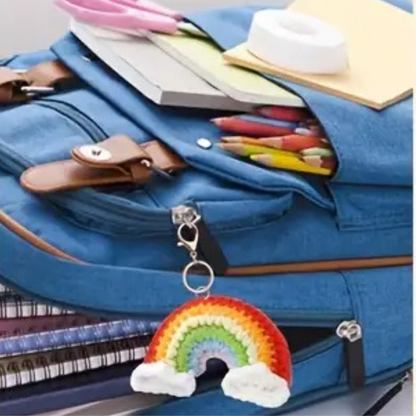 A blue backpack with colored pencils, notebooks, and stationery, featuring a keychain from the Crochet Keychain Kit 4pcs attached to the zipper.
