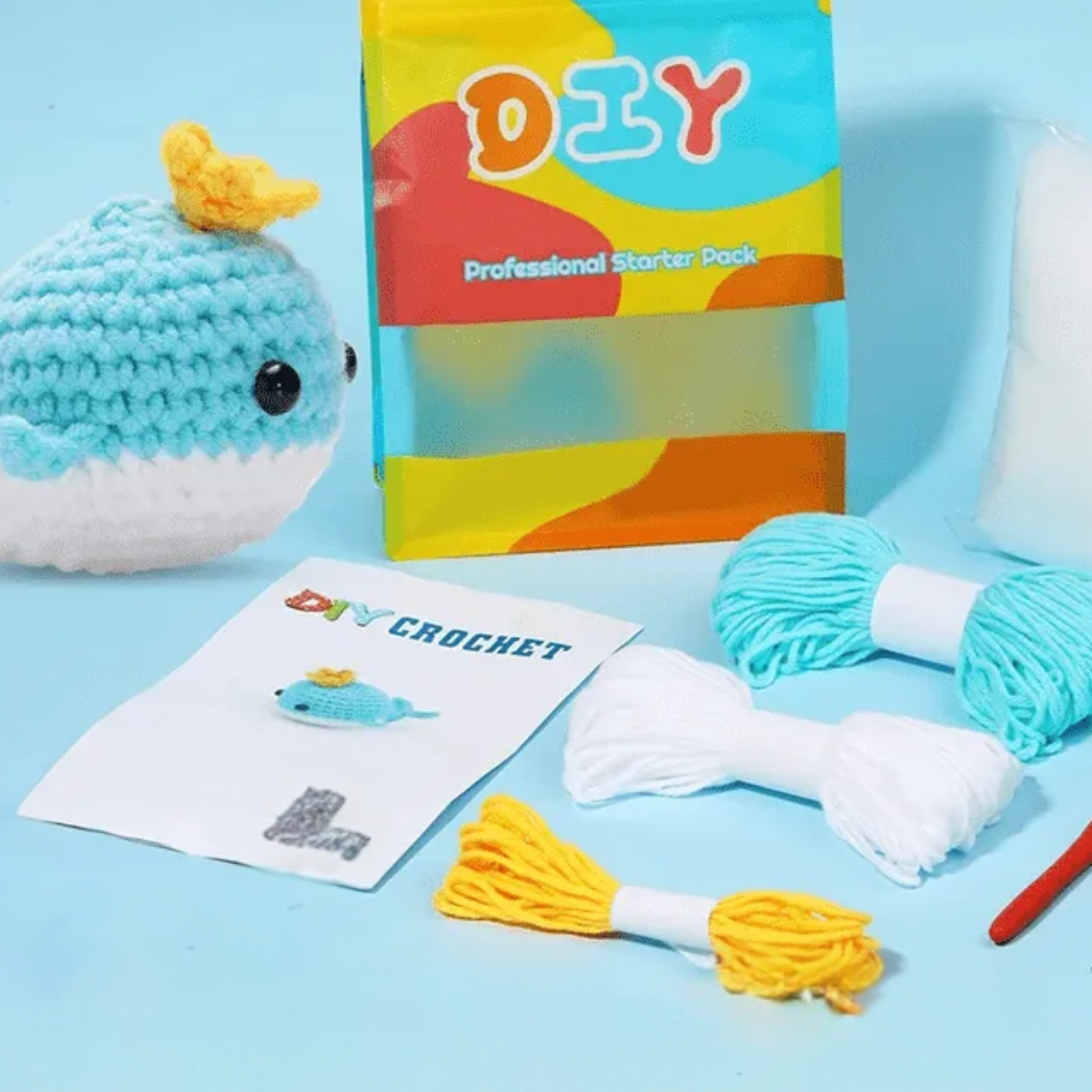 The Crochet Whale Kit 2pcs includes yarn, crochet hook, stuffing, pattern sheet, and materials to make a blue whale with a yellow crown—ideal for beginner crochet fans or anyone wanting a fun whale project.