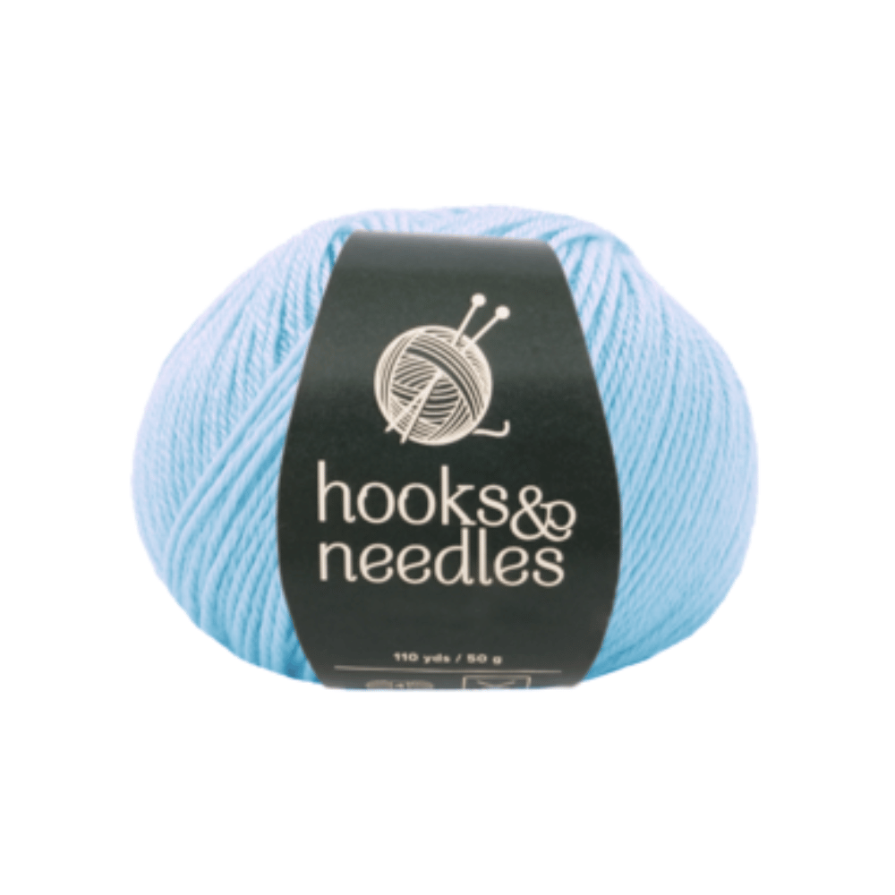 A ball of Fuzzy Whirl Yarn 100g, in a light blue acrylic, showcases a knitting needles and yarn logo on the "hooks & needles" label. This Aran weight yarn is ideal for cozy projects.