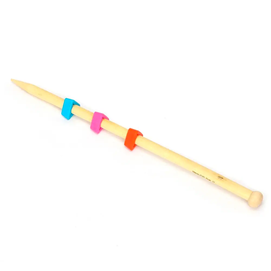 The Knitting Needles Tip Protectors 18pcs set includes a wooden knitting needle accompanied by three multicolored stitch markers—in blue, pink, and orange—and silicone needle covers to ensure snag-free protection for your yarn.