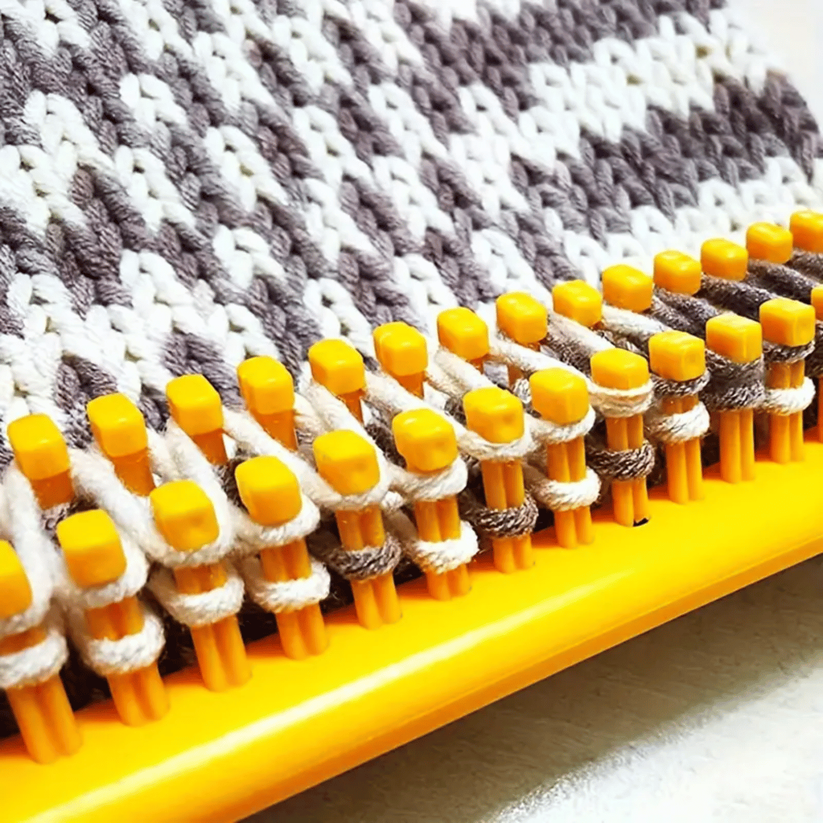 Close-up of the Knitting Loom Set in yellow with brown and white yarn, creating a patterned fabric—ideal for easy projects and beginners.